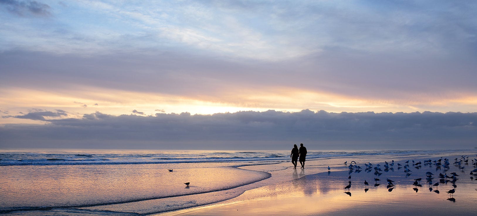 Couple walk together at sunset on the beach