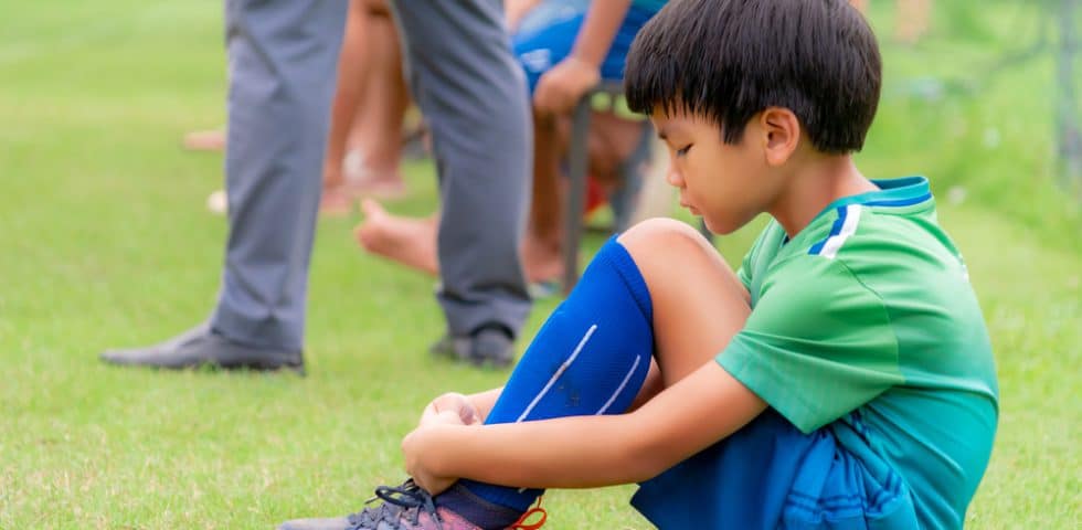 Disappointed boy sits on soccer field after losing a game
