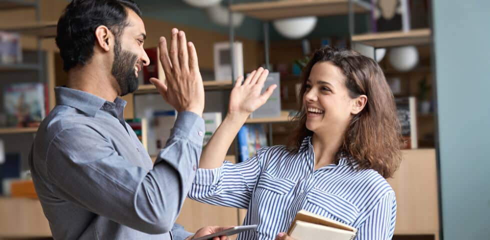 Two friends high-fiving and smiling; the neuroscience of behavior change